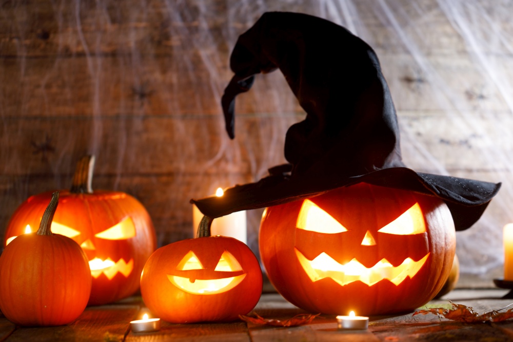 Festive mystical halloween interior. Pumpkin, spider web, burning candles, spiders on dark wooden background. Festive mystical halloween pumpkins