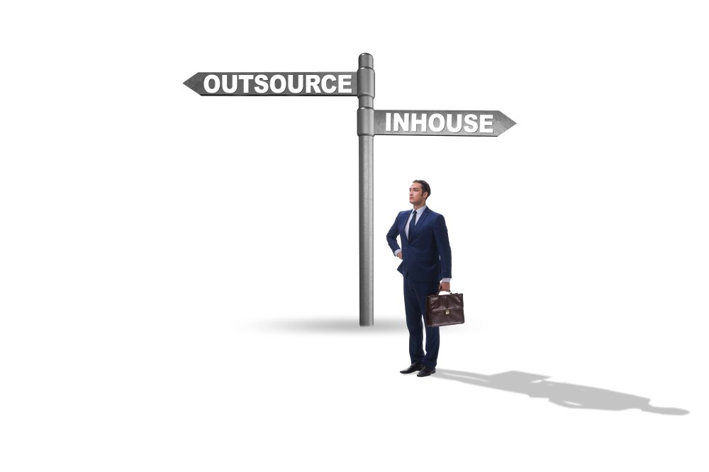 Businessman at crossroads deciding between outsourcing and inhouse . Businessman at crossroads deciding between outsourcing and inhou
