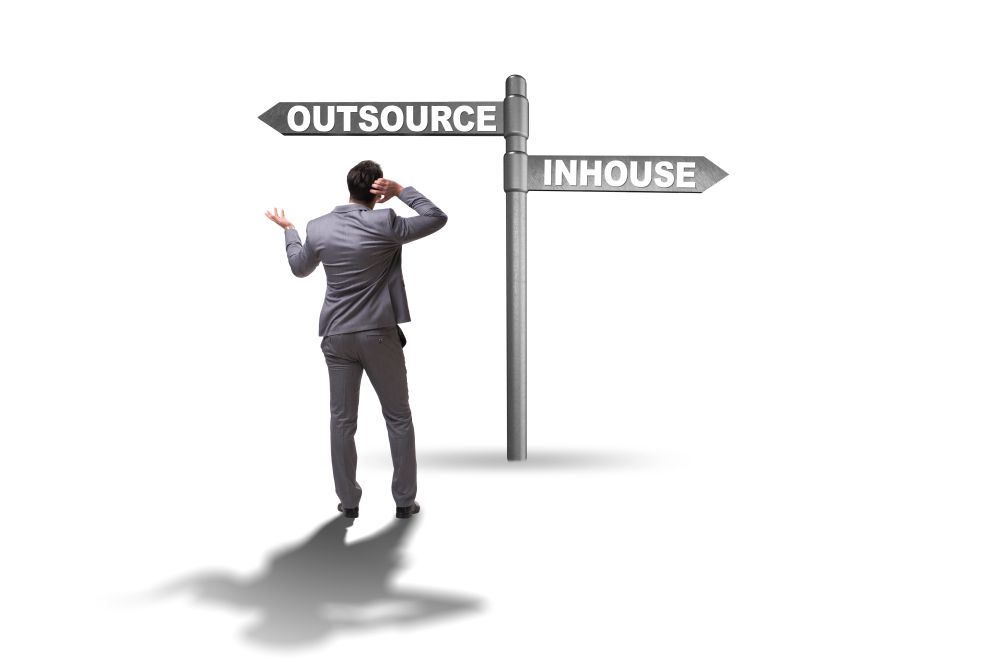 Businessman at crossroads deciding between outsourcing and inhouse . Businessman deciding between outsourcing and inhouse