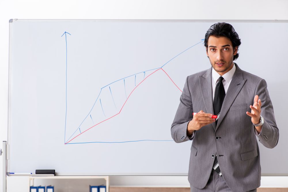 The young handsome businessman in front of whiteboard . Young handsome businessman in front of whiteboard