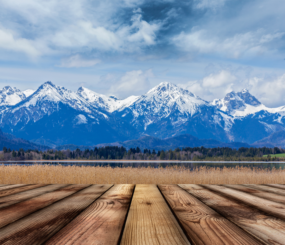 Wooden planks floor with Bavarian Alps countryside lake landscape in background. Bavaria, Germany. Wooden planks floor with Bavarian Alps landscape