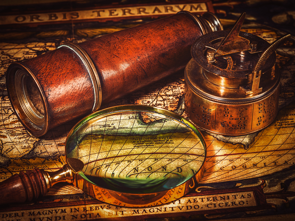 Travel geography navigation concept background - vintage retro effect filtered hipster style image of old vintage retro compass with sundial, spyglass and magnifying glass on ancient world map. Old vintage compass on ancient map
