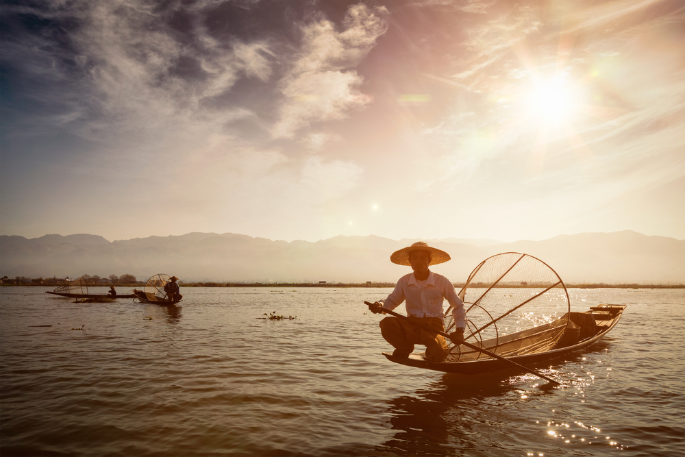 Myanmar travel attraction landmark - Traditional Burmese fisherman at Inle lake, Myanmar famous for their distinctive one legged rowing style.  Traditional Burmese fisherman at Inle lake, Myanmar