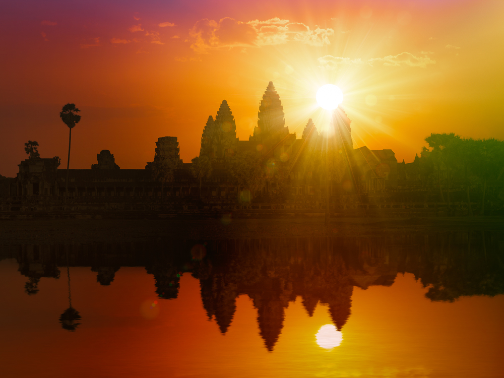 Cambodia landmark Angkor Wat silhouette with reflection in water on sunset. With lens flare and light leak. Angkor Wat on sunset