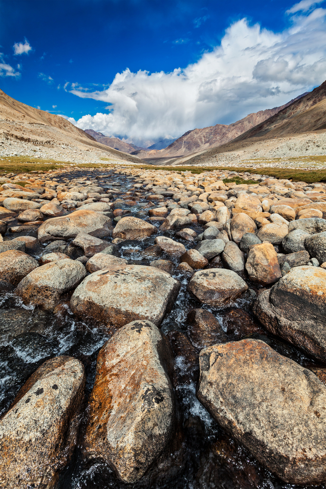Mountain stream with stones in Himalayas near Khardung La pass. Ladakh, Jammu and Kashmir, India. Mountain stream with stones in Himalayas