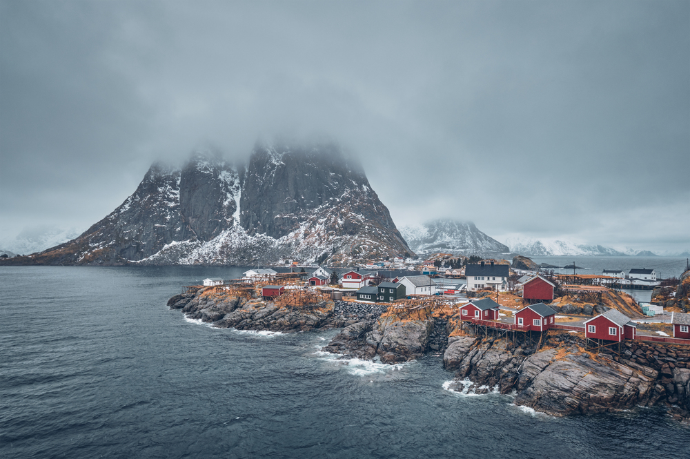 Famous tourist attraction Hamnoy fishing village on Lofoten Islands, Norway with red rorbu houses. With falling snow in winter. Hamnoy fishing village on Lofoten Islands, Norway
