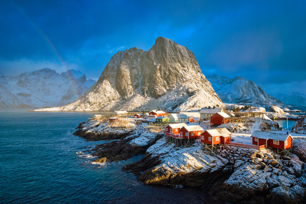 Hamnoy fishing village on Lofoten Islands, Norway with red rorbu houses. With falling snow in winter and rainbow. Hamnoy fishing village on Lofoten Islands, Norway