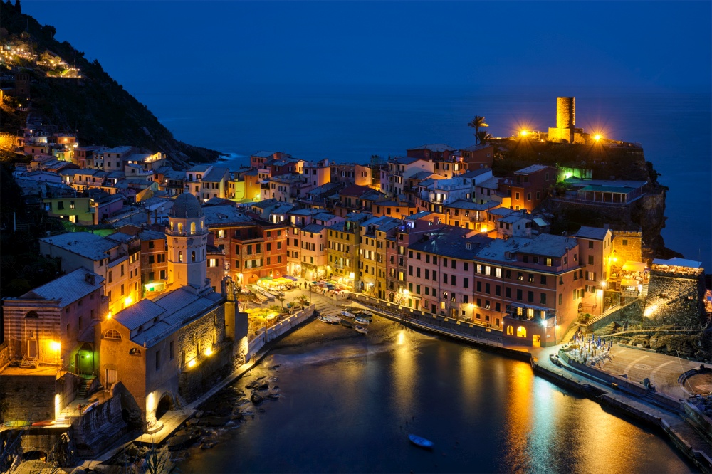 View of Vernazza village popular tourist destination in Cinque Terre National Park a UNESCO World Heritage Site, Liguria, Italy view illuminated in the night from Azure trail. Vernazza village illuminated in the night, Cinque Terre, Liguria, Italy