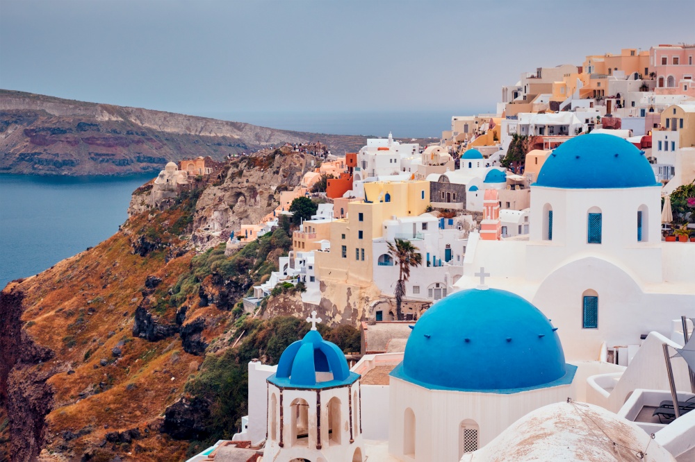 Famous greek iconic selfie spot tourist destination Oia village with traditional white houses and church in Santorini island on sunset in twilight, Greece. Famous greek tourist destination Oia, Greece