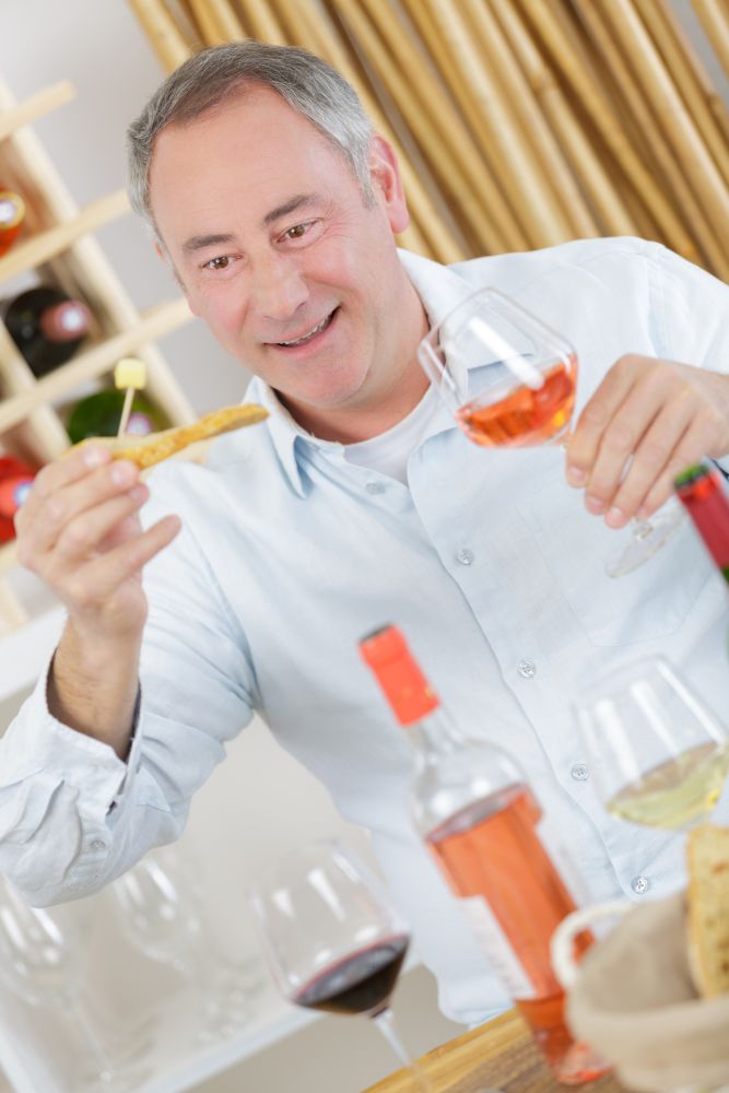 handsome mature man tasting glass of rose wine