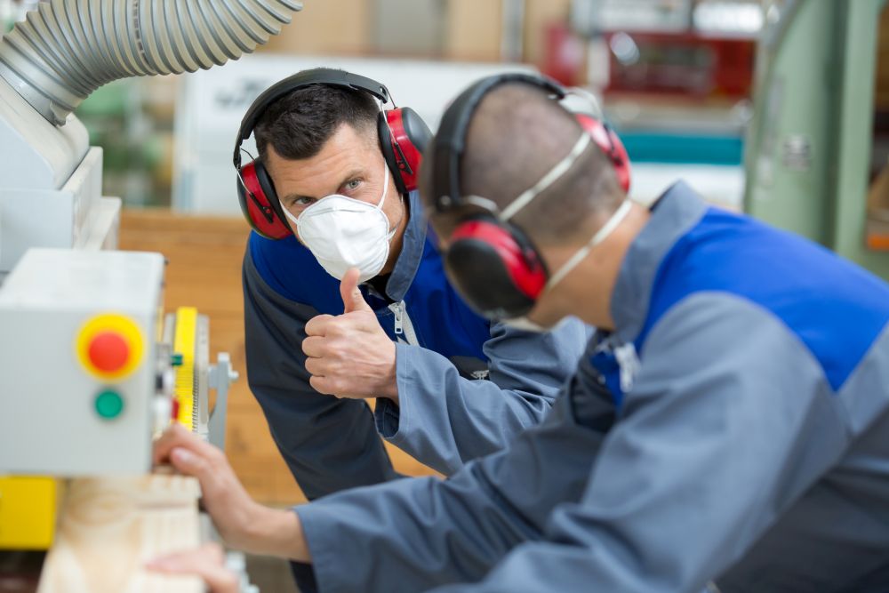 supervisor wearing dust mask giving thumbs up to worker