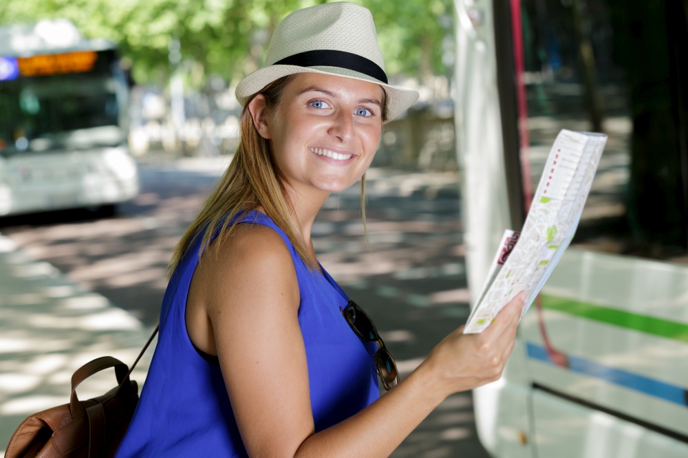 happy female tourist on location map to bus station vacation