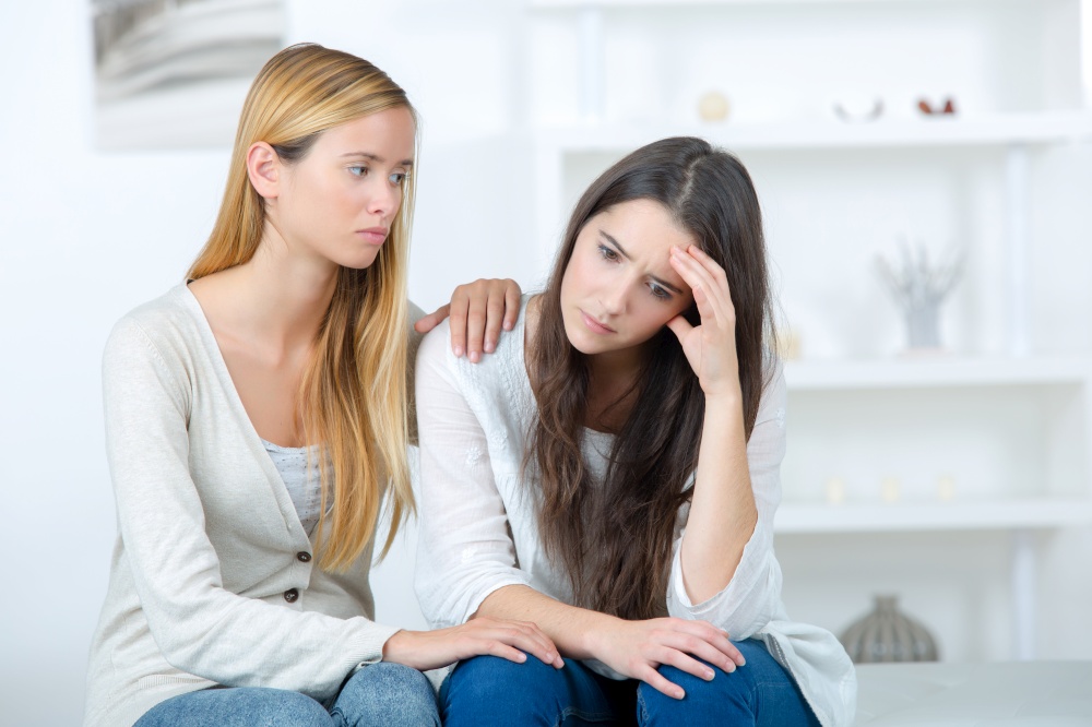 young woman is sad crying and being consoled by friend