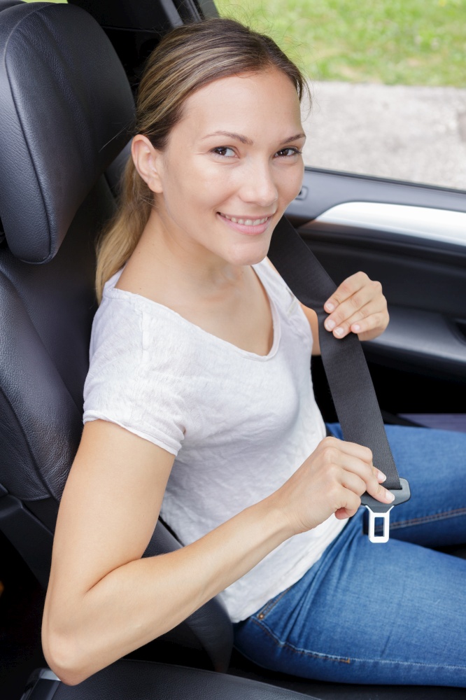 portrait of attractive young woman fastening her seatbelt
