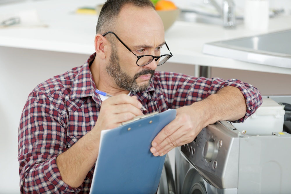 washing machine serviceman looking over top of glasses to write