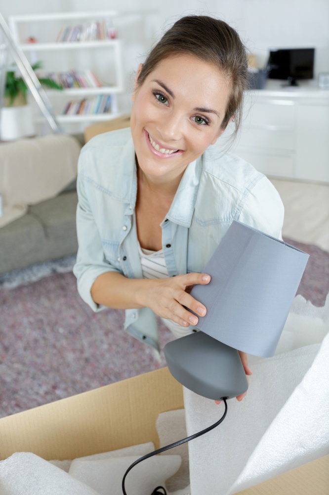 woman unpacking a lamp from a cardboard box