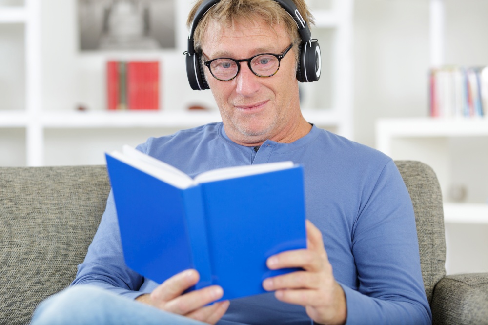 man with headphones listening and reading at home