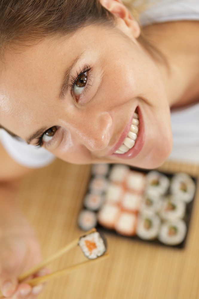 high angle view of woman holding sushi between chopsticks