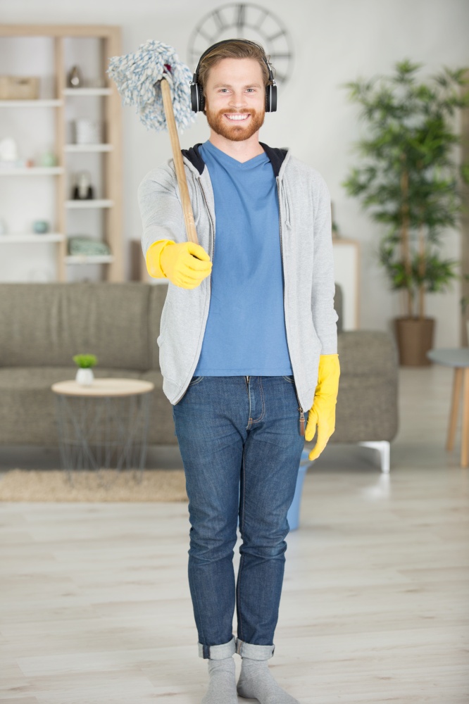 man standing to attention with a mop on his shoulder