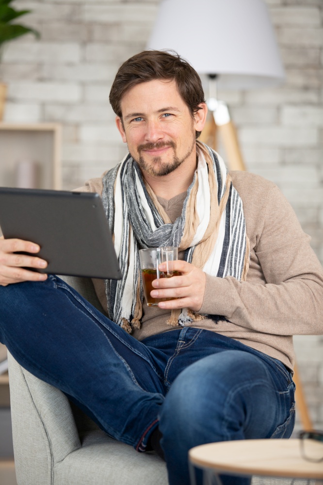man holding tablet surfing online and drinking coffee