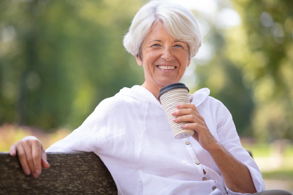 senior woman drinking take away coffee in the park