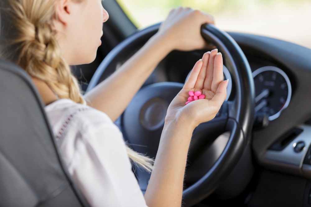 woman with tablets while steering the car