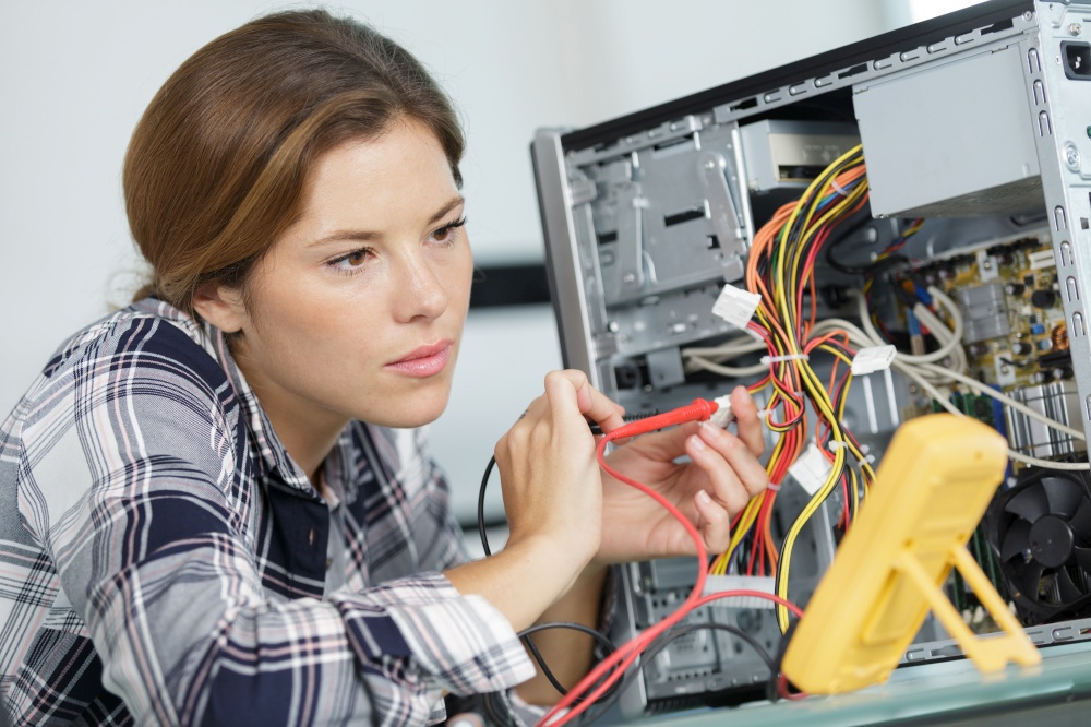woman checking computer with a multimeter
