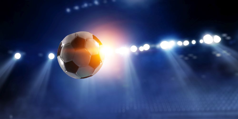 Soccer ball against dark blue lighted stadium background. Soccer ball flight over stadium