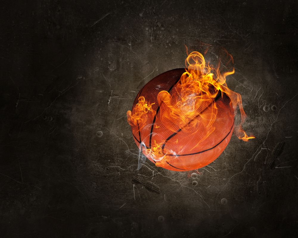 Ball in fire flames on dark background. Mixed media. Basketball game concept