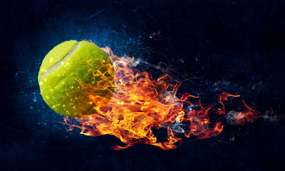 Big tennis ball in fire flames on dark background. Mixed media. Tennis ball in fire