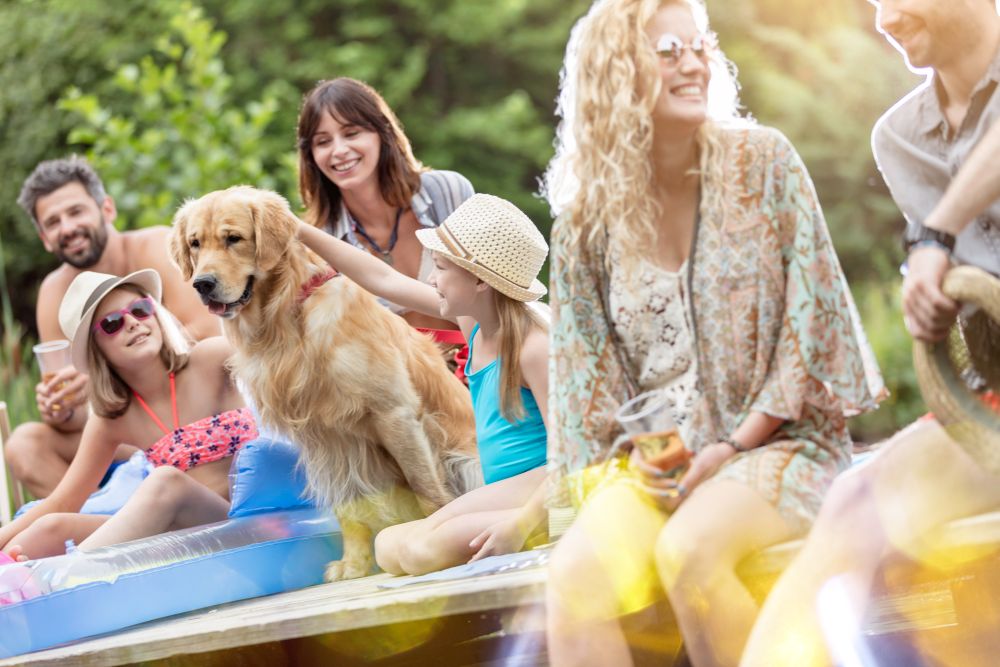 Family and friends sitting with Golden retriever on pier