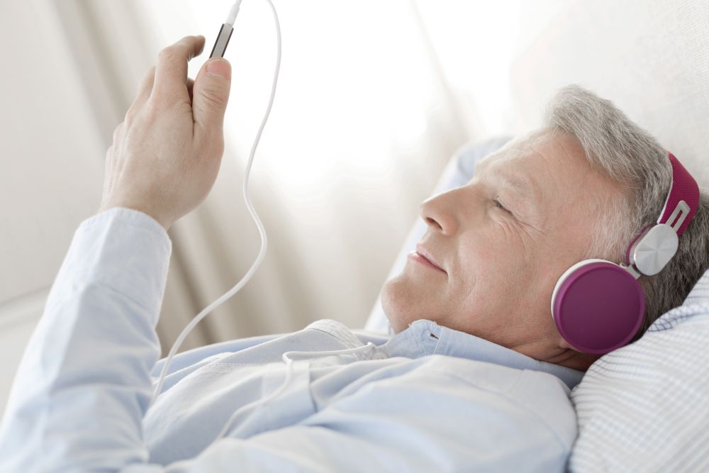 Mature man listening music while lying in bedroom at home