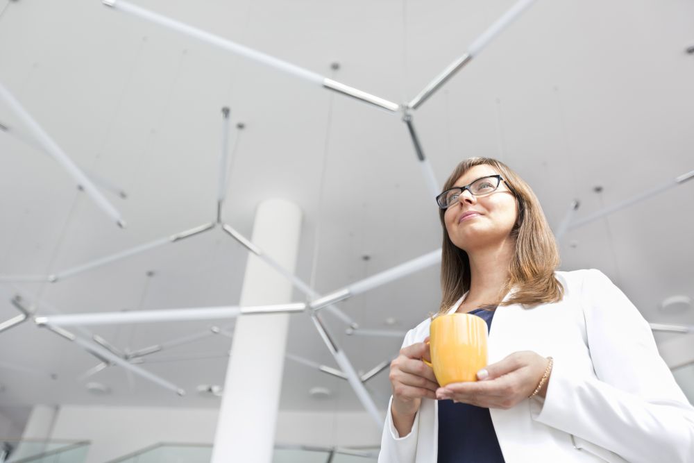 Low angle view of businesswoman holding coffee mug while standing at office