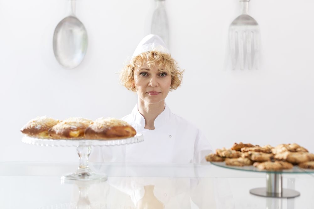 Portrait of confident mature chef standing at display cabinet in restaurant