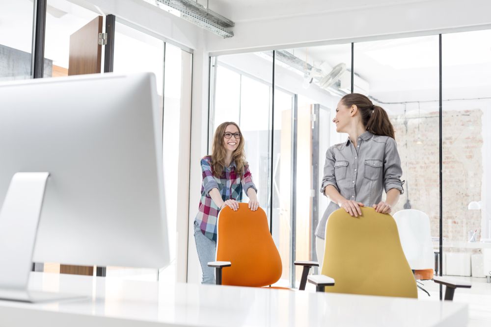 Businesswomen pushing chairs in new office