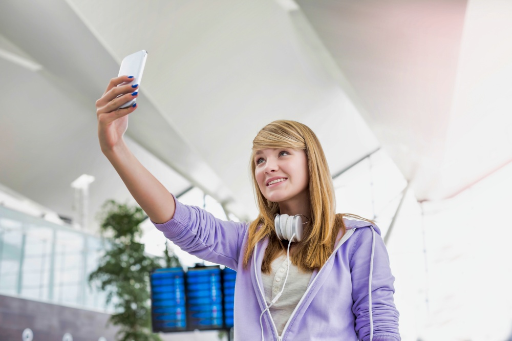 Young attractive teenage girl taking selfie in airport