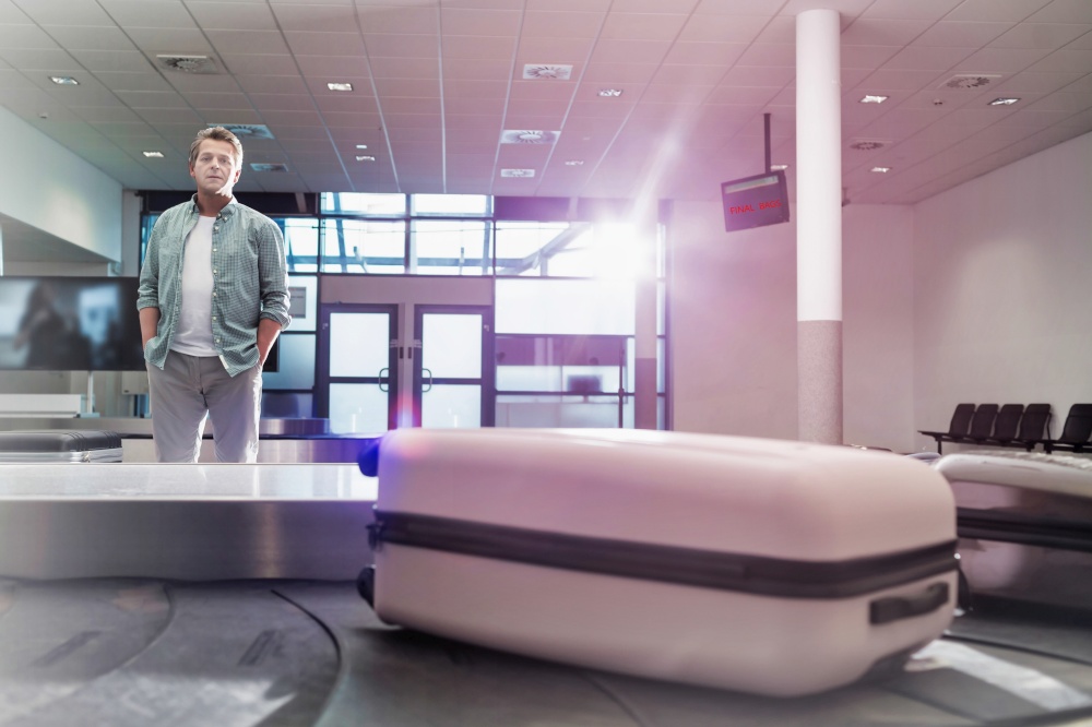 Mature man waiting for his suit case on baggage claiming area in airport