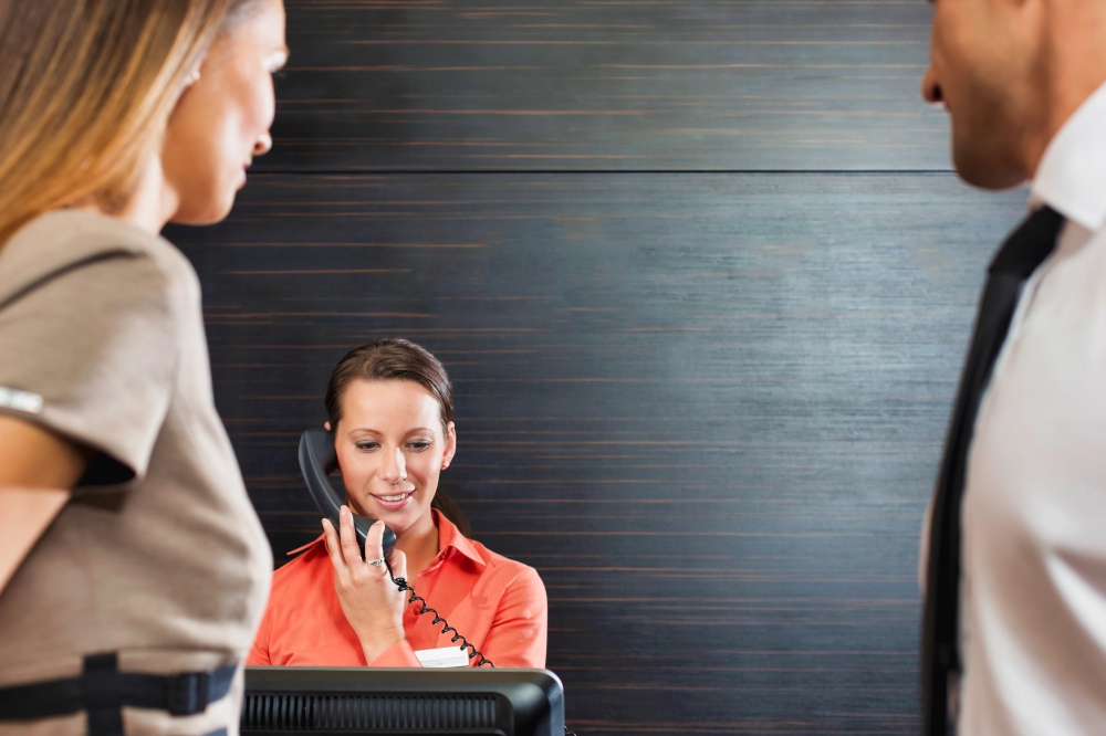 Receptionist calling for assistance while business people waiting in lobby