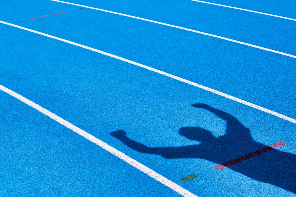 Shadow of an athlete celebrating success in finish line