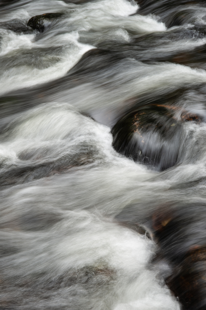 Detail landscape image of river flowing over rocks with long exposure motion blur