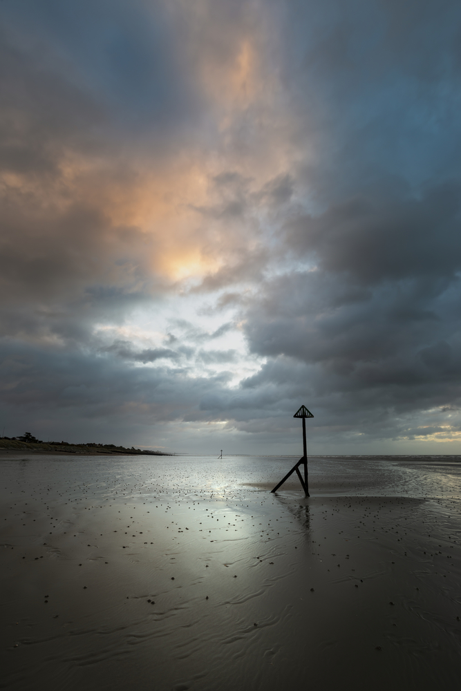 Beautiful Winter sunrise over West Wittering beach in Sussex England with wind blowing sand across the beach