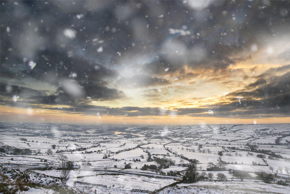 Winter sky over snow covered Winter landscape in Peak District at sunset in heavy snow storm. Landscapes
