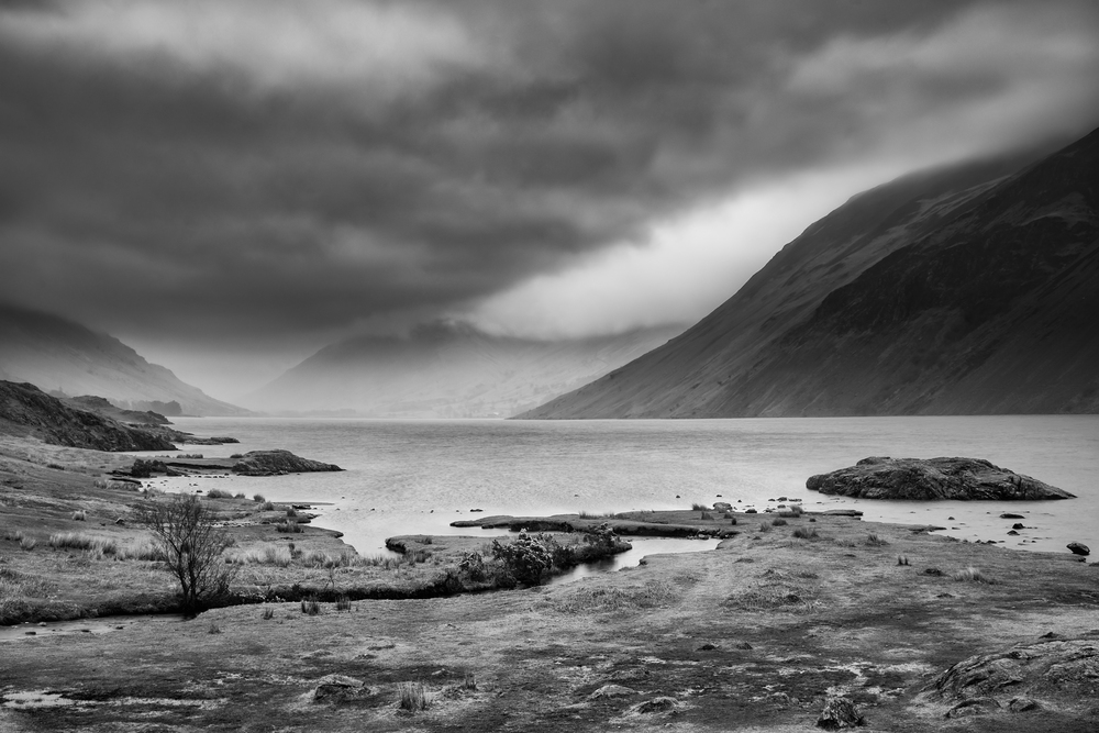 Beautiful long exposure landscape image of Wast Water in UK Lake District during moody Spring evening in black and white