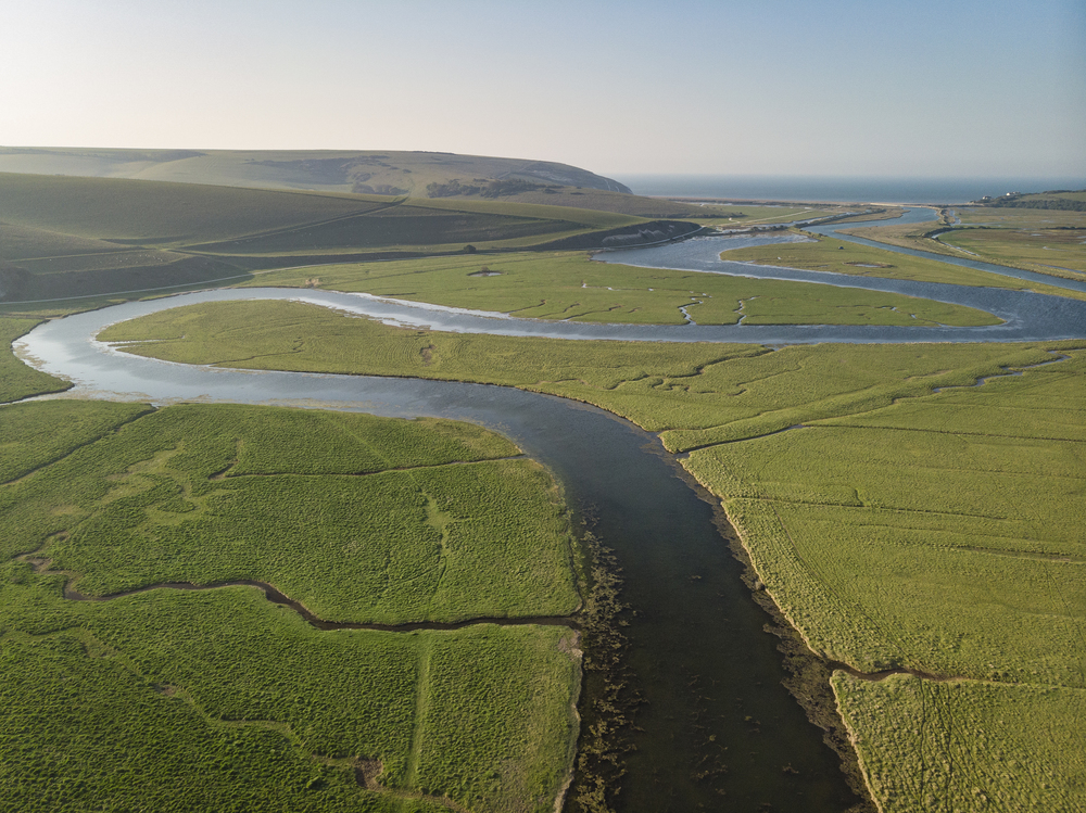 Beautiful aerial drone landscape image of meandering river through marshland at sunrise