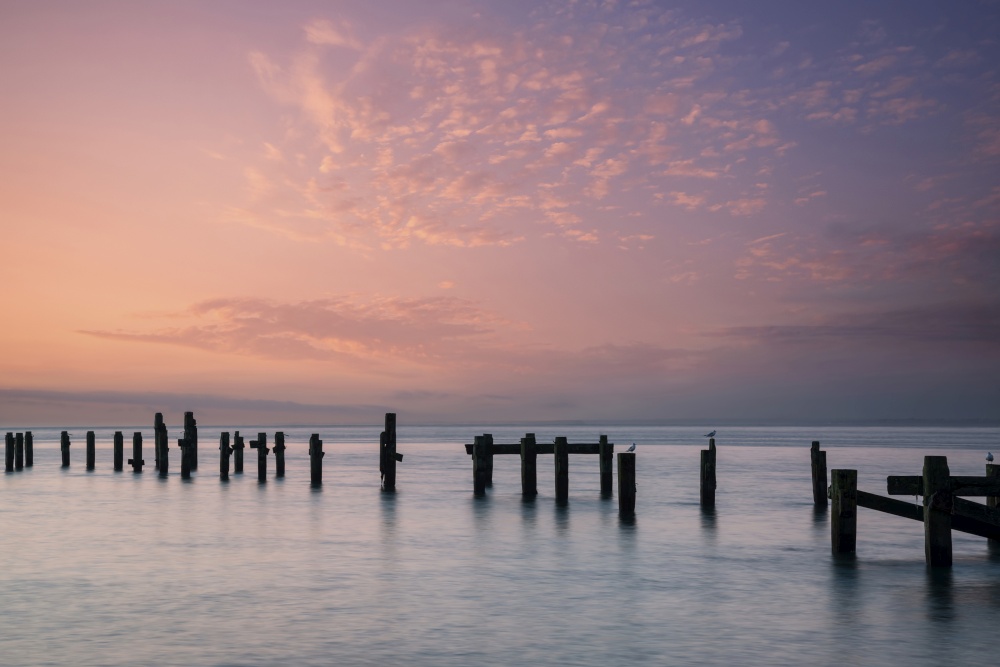 Beautiful calm sea landscape of old derelict pier foundations at sunrise