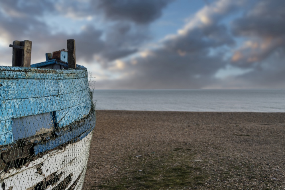 Old abandoned fishing boat on beach with shallow depth of field