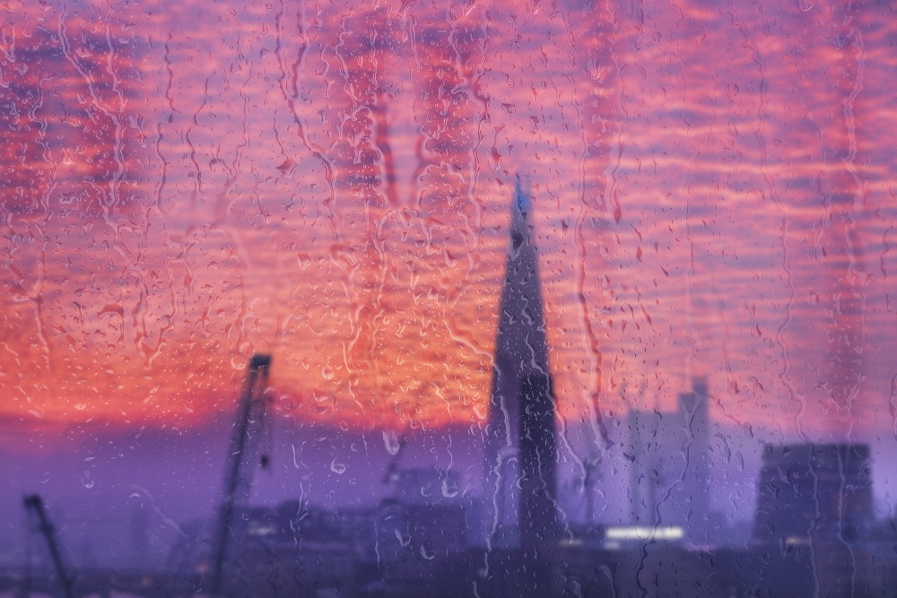 Beautiful landscape conceptual view of London City through glass window with raindrops running down the glass