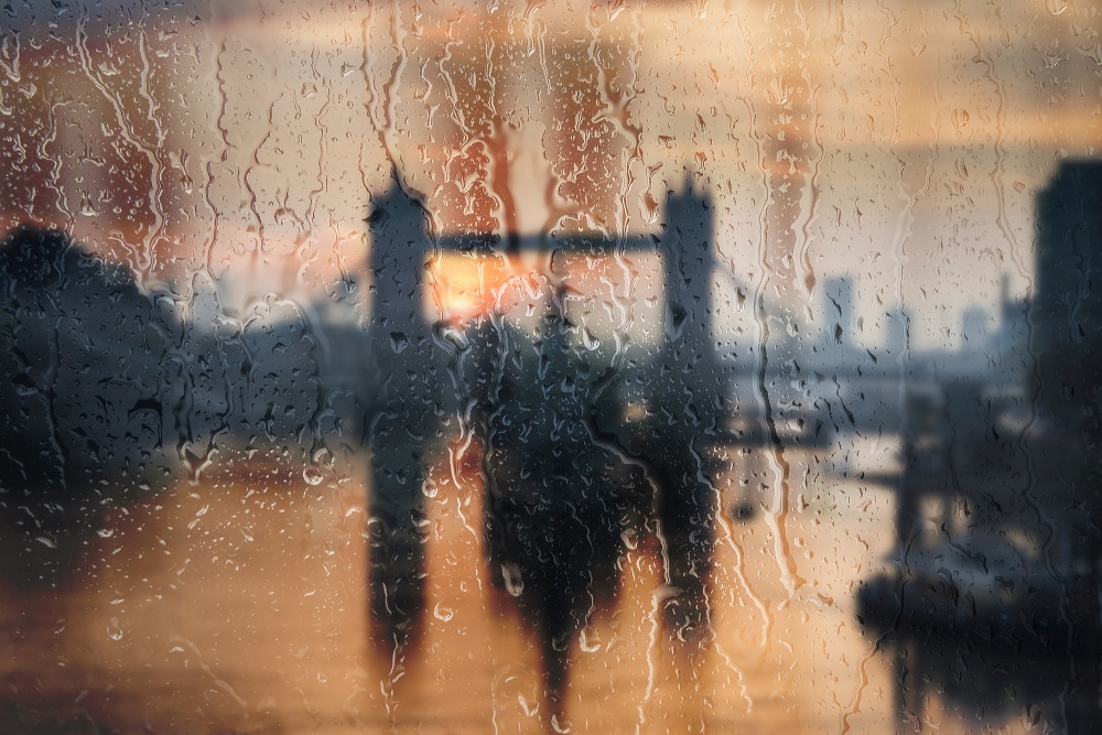 Beautiful landscape conceptual view of London City through glass window with raindrops running down the glass