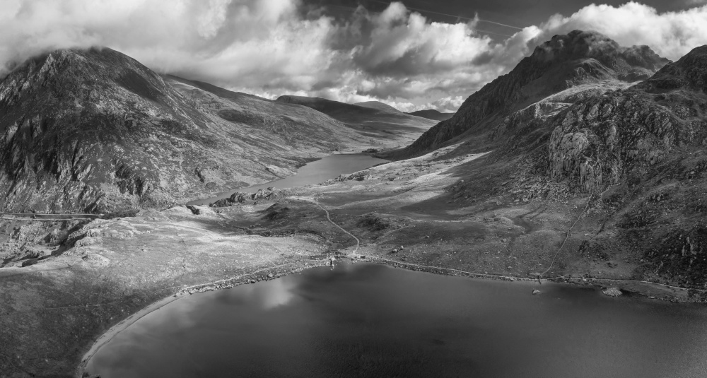 Black and white Aerial view of flying drone Epic early Autumn Fall landscape image of view along Ogwen vslley in Snowdonia National Park with dramatic sky and mountains