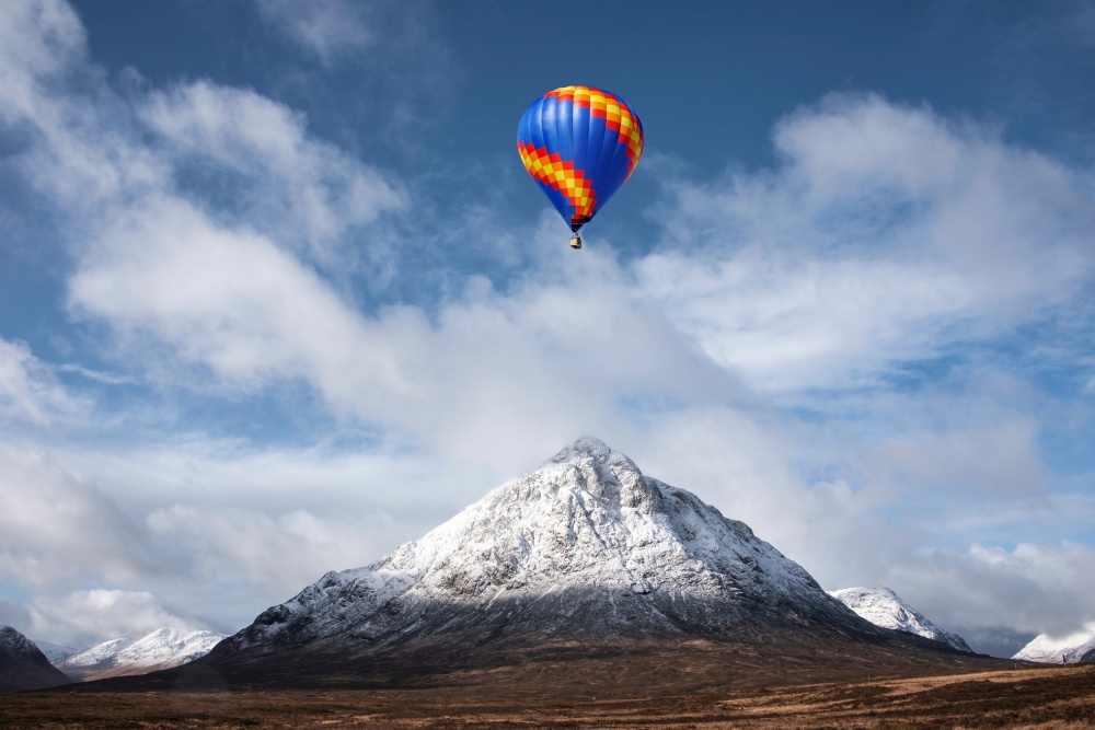 Digital composite image of hot air balloons flying over Stunning iconic landscape Winter image of Stob Dearg Buachaille Etive Mor mountain in Scottish Highlands